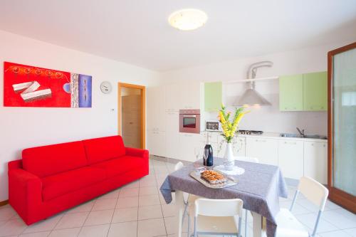 a living room with a red couch and a table at RESORT VILLAGE AQUA MARINA FAMILY - Daily Rooms Tidying - CocktailsBar- Pet Friendly - with Hypermarket - Delivery Restaurant-Pizzeria - Room Breakfast with supplement - Ultra Fast Wi-Fi - Play Area for children - Olympic Swimming Pool - Parking in Caorle