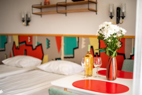 a table with two glasses and a bottle of wine and flowers at MyRiviéra Apartman in Balatonfüred