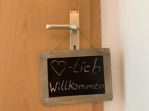 a chalkboard hanging on a door with the words hello willuminati at Moderne Ferienwohnung für 5 Gäste in Oberwiesenthal in Kurort Oberwiesenthal