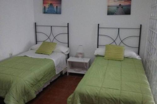 twee bedden in een kamer met groene lakens bij Apartamento Soleado in Tarifa