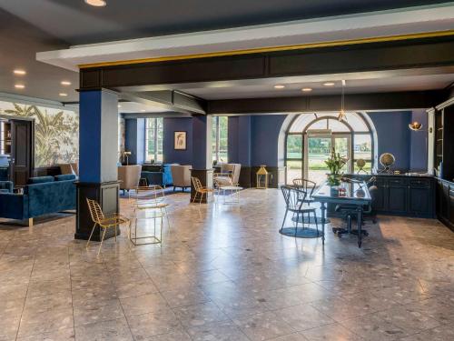 a lobby with chairs and tables in a building at Hôtel Mercure Rochefort La Corderie Royale in Rochefort