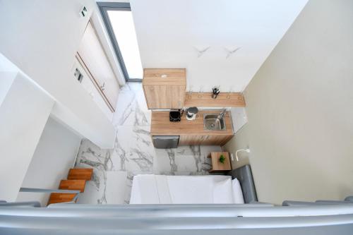 a small attic room with white furniture and a staircase at Alos Utopia in Stavros