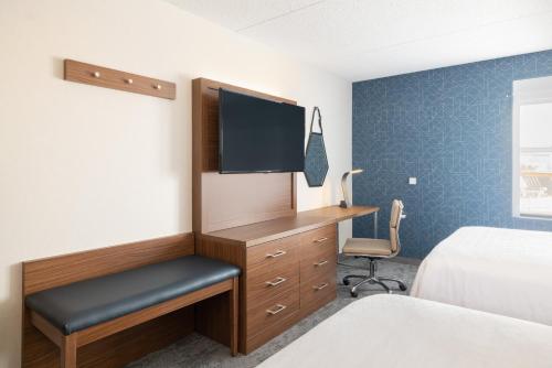 a bedroom with a desk with a tv and a chair at Holiday Inn Express & Suites Boston - Cambridge by IHG in Cambridge