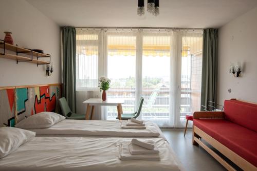 a bedroom with two beds and a table and a window at MyRiviéra Apartman in Balatonfüred