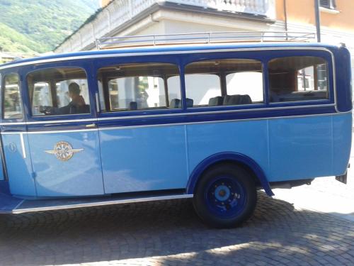 a blue bus is parked on a street at Hotel Bed & Rooms , Corte Rossa -1 Min Walk To Bernina Express in Tirano