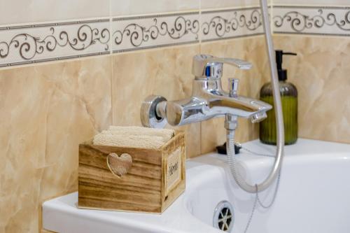 a bathroom sink with a faucet and a wooden box at Гостерія"Old Town" in Kamianets-Podilskyi