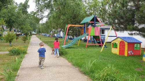 dos niños caminando por una acera junto a un parque infantil en Satul de Vacanta Campo Euro Club, en Partizanii