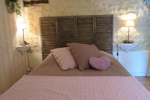 a bed with two pillows and a heart pillow on it at La Naomath - Maison d'hôtes, Hébergement insolite & Gîte in Bayeux