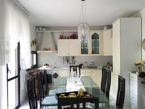 una cucina con tavolo in vetro e armadietti bianchi di CASA Lux a Serravalle Pistoiese