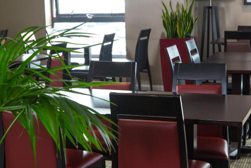 a restaurant with tables and chairs and plants at Holiday Inn Express London Luton Airport by IHG in Luton
