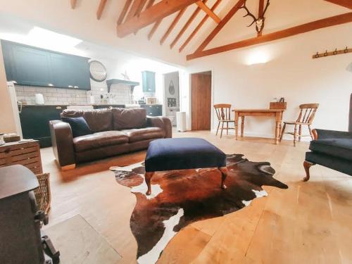 a living room with a cow rug on the floor at 7 Grove Farm Barns in Sculthorpe