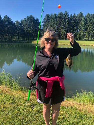 a woman standing next to a lake holding a fishing pole at Pinehaven Country Inn in Baraboo