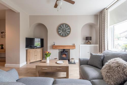 a living room with a couch and a clock on the wall at Dales Edge - Skipton in Skipton