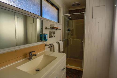 y baño con lavabo, espejo y ducha. en Mountain View Motor Inn & Holiday Lodges en Halls Gap