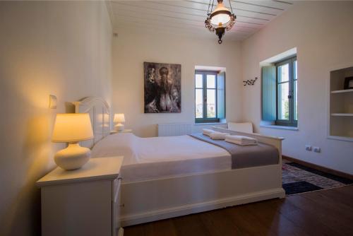 una camera da letto con un grande letto bianco e una lampada di Laconian Collection Villa Magoula a Sparta