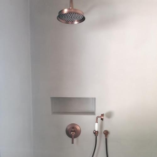 a bathroom with a shower with a light on the wall at Hôtel Les Suites Du Maquis in Bonifacio