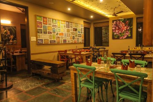 a restaurant with wooden tables and green chairs at Tathastu Pench in Khawāsa