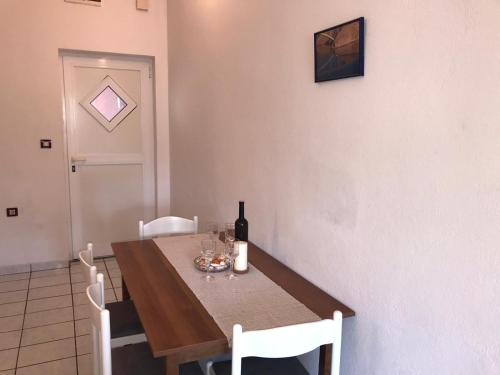 a dining room table with a bottle of wine on it at apartmani radoslovic in Pag