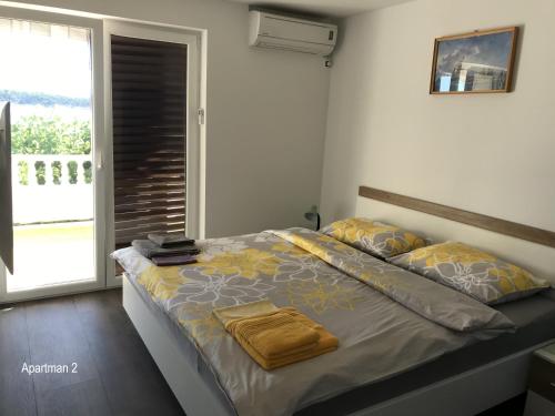 a bedroom with a bed with yellow sheets and a window at Apartment One in Rab