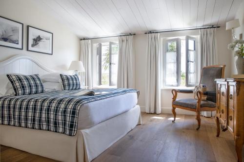 a bedroom with a bed and a chair and windows at Villa Clarisse & Spa by Olivier Claire in Saint-Martin-de-Ré