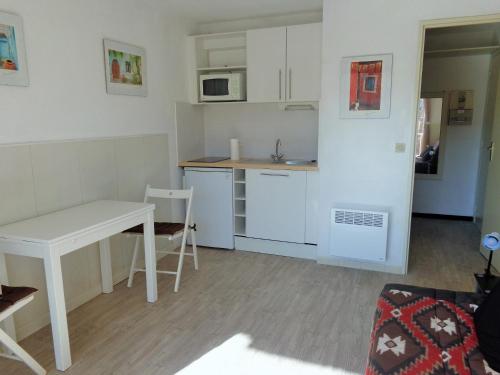 eine kleine Küche mit einem weißen Tisch und einem Tisch in der Unterkunft STUDIO 2 PERS QUARTIER DES PLAGES DE LA CORNICHE in Sète