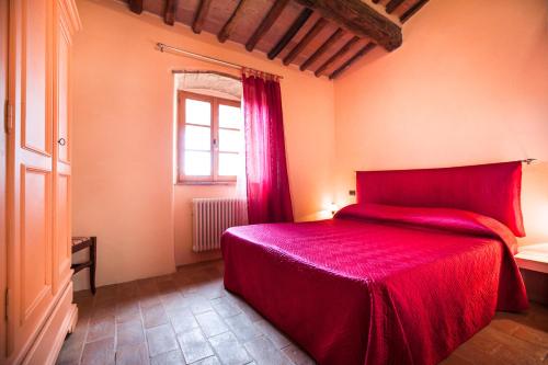 a bedroom with a red bed and a window at Fattoria Le Fonti in Poggibonsi
