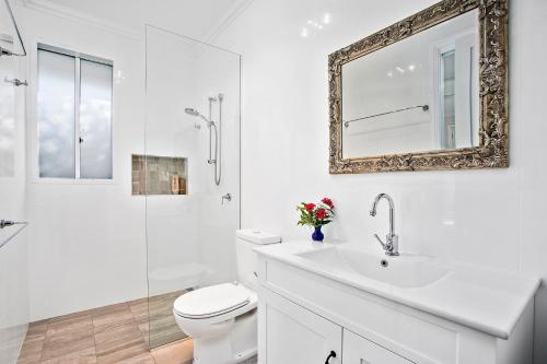 a bathroom with a toilet and a sink and a mirror at Jetty Splendour Guest Bedroom with Bathroom en-suite B'nB in Coffs Harbour
