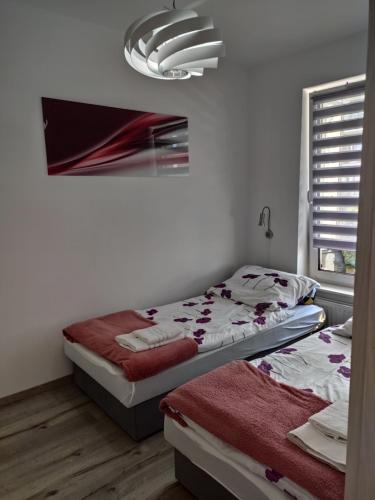 a bedroom with two beds and a chandelier at Kołobrzeg apartament Osiedle Bursztynowe ul baltycka 11 b in Kołobrzeg