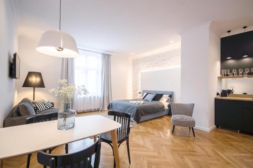 uma sala de estar com uma cama, uma mesa e cadeiras em Wanderlust Apartments em Cracóvia