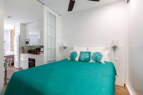 Chamberí Design Loft في مدريد: غرفة نوم بسرير اخضر مع مطبخ في الخلفية