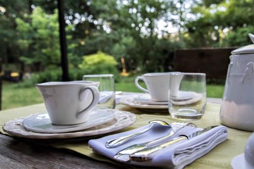 een tafel met twee kopjes, borden en glazen bij La Closerie de Sarlat Maison d hôtes de charme in Sainte-Nathalène