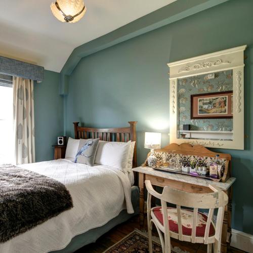 a bedroom with a bed and a table with a mirror at Victoria House in Church Stretton