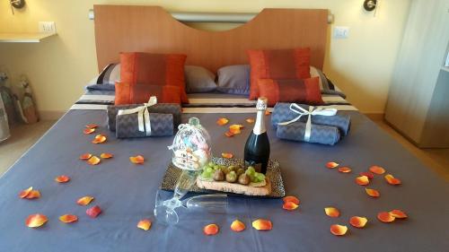 ein Bett mit einem Tisch mit einer Flasche Wein und Obst darauf in der Unterkunft B & B La Magia in Iglesias