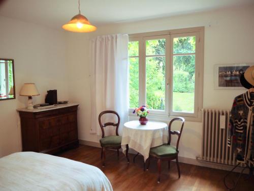 a bedroom with a table and chairs and a window at Cour Tholmer in Touques