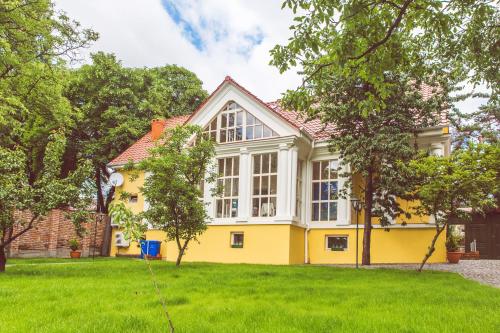 a yellow house with white windows and a yard at Boutique Hotel Villa P in Uzhhorod