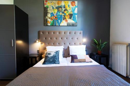 a bedroom with a bed and a painting on the wall at Quentin England Hotel in Amsterdam