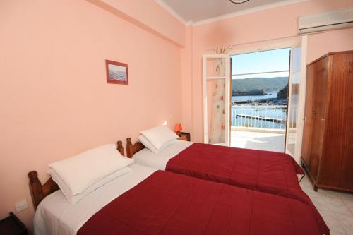 two beds in a bedroom with a view of the water at Molos Beach Apartments in Paleokastritsa