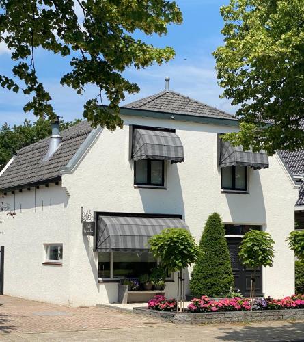 a white house with black awnings on it at B&B Bij tante Teun in Naaldwijk