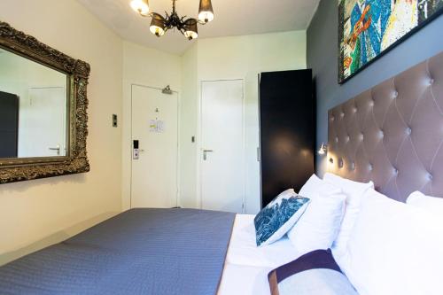 a bedroom with a large bed and a mirror at Quentin England Hotel in Amsterdam
