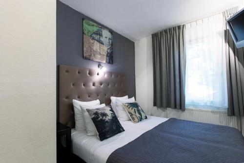a hotel room with a bed with pillows at Quentin England Hotel in Amsterdam