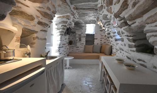 una cocina con una pared de piedra y un sofá. en Tranquil cottage, en Agios Sostis