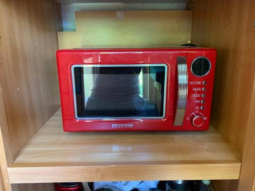 a red microwave sitting on top of a shelf at Mysig husvagn in Romakloster