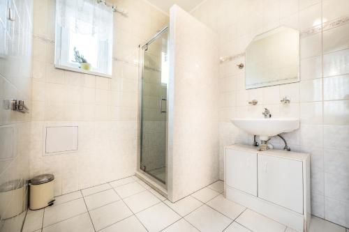a white bathroom with a sink and a shower at Penzion U Kostela in Mikulčice