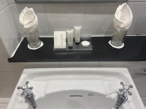 a white sink in a bathroom with glasses on a counter at Hatherley Manor Hotel & Spa in Gloucester