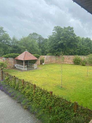 a garden with a gazebo and a wall at Hatherley Manor Hotel & Spa in Gloucester