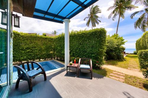 a patio with two chairs and a table next to a pool at Sea Valley Resort in Lipa Noi