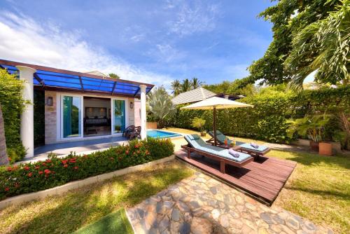 a patio with an umbrella and chairs next to a house at Sea Valley Resort in Lipa Noi