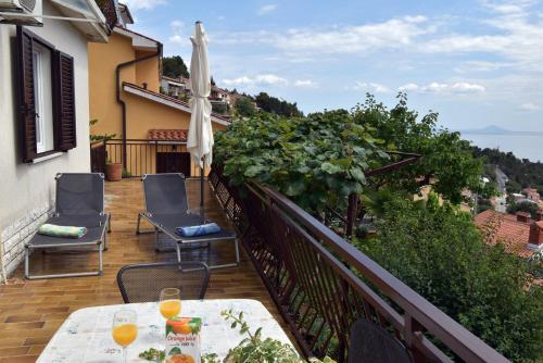 a balcony with a table and chairs and an umbrella at Apartment Neda in Rabac
