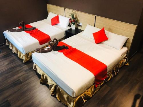 two beds with red and white pillows in a room at Highway Times Inn Hotel in Ipoh