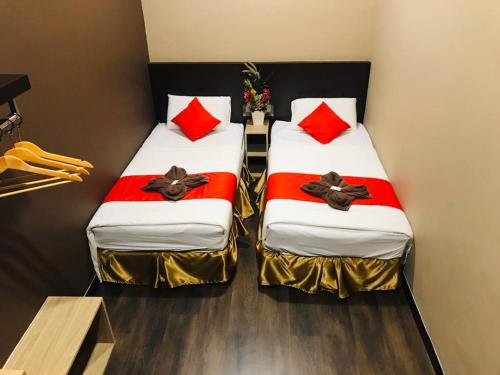 two beds in a room with red pillows at Highway Times Inn Hotel in Ipoh